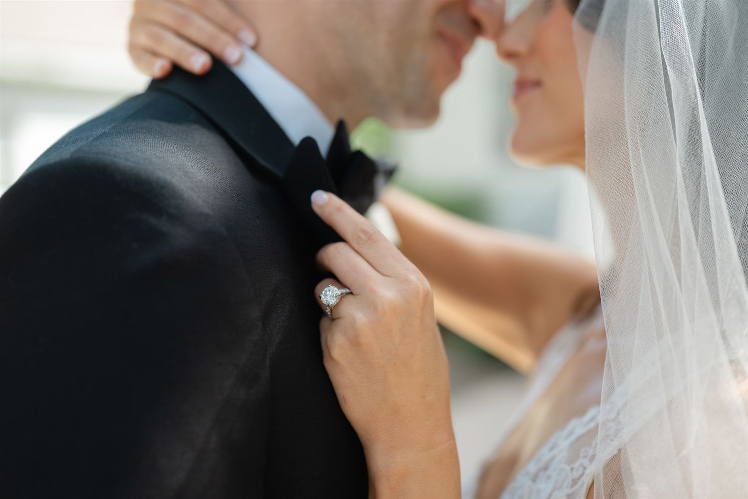 Bride and groom sharing an intimate moment, showcasing a stunning diamond engagement ring and wedding veil.