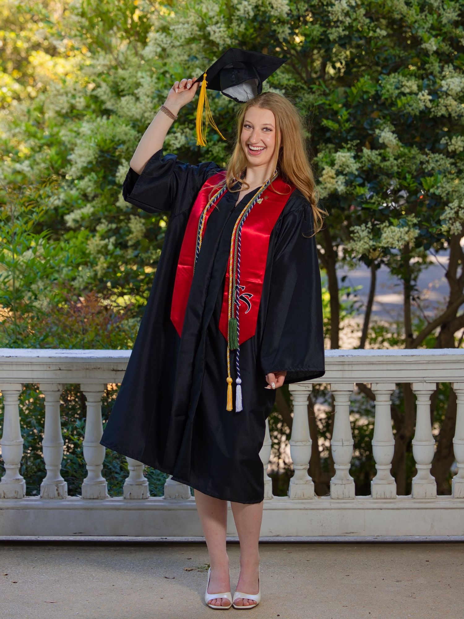 Portrait photo by Jeff Heveron of a woman in her graduation cap and gown posing for the picture.