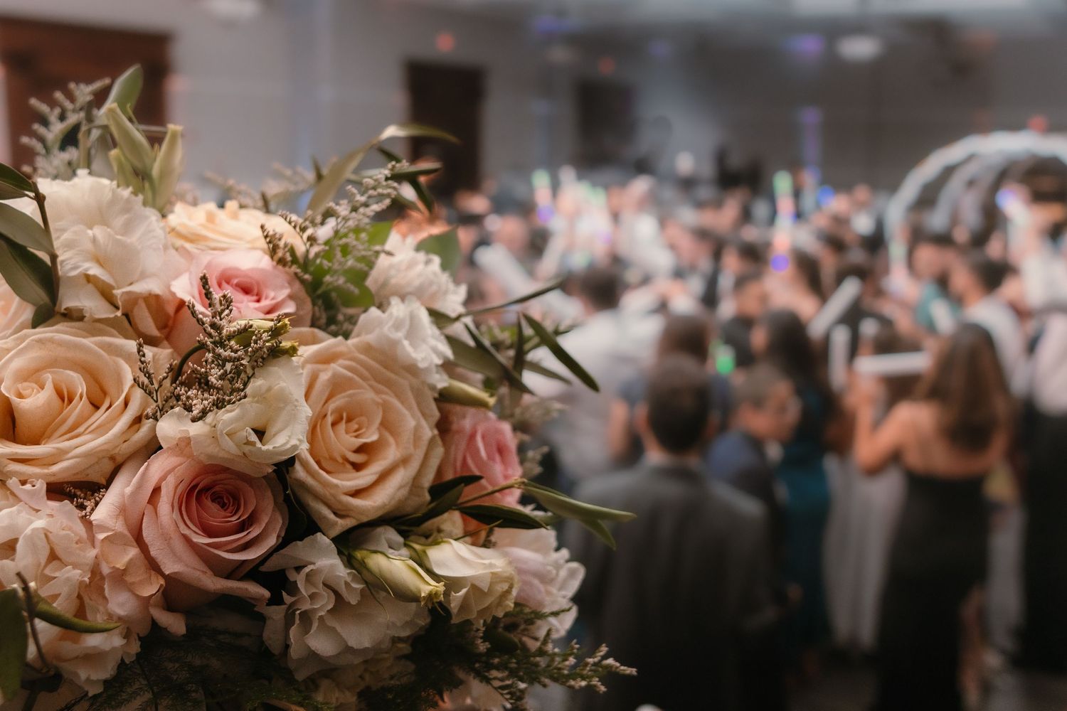 A bouquet of flowers beautifully arranged with a large crowd in the background at an event.