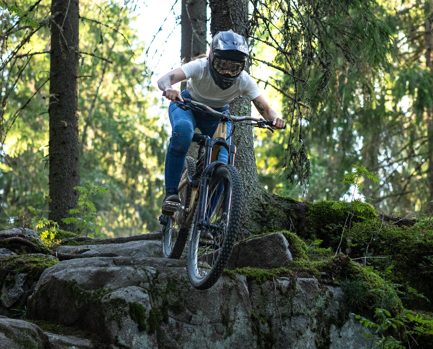 Mountain biker navigates rocky terrain on a challenging forest trail during a downhill descent.