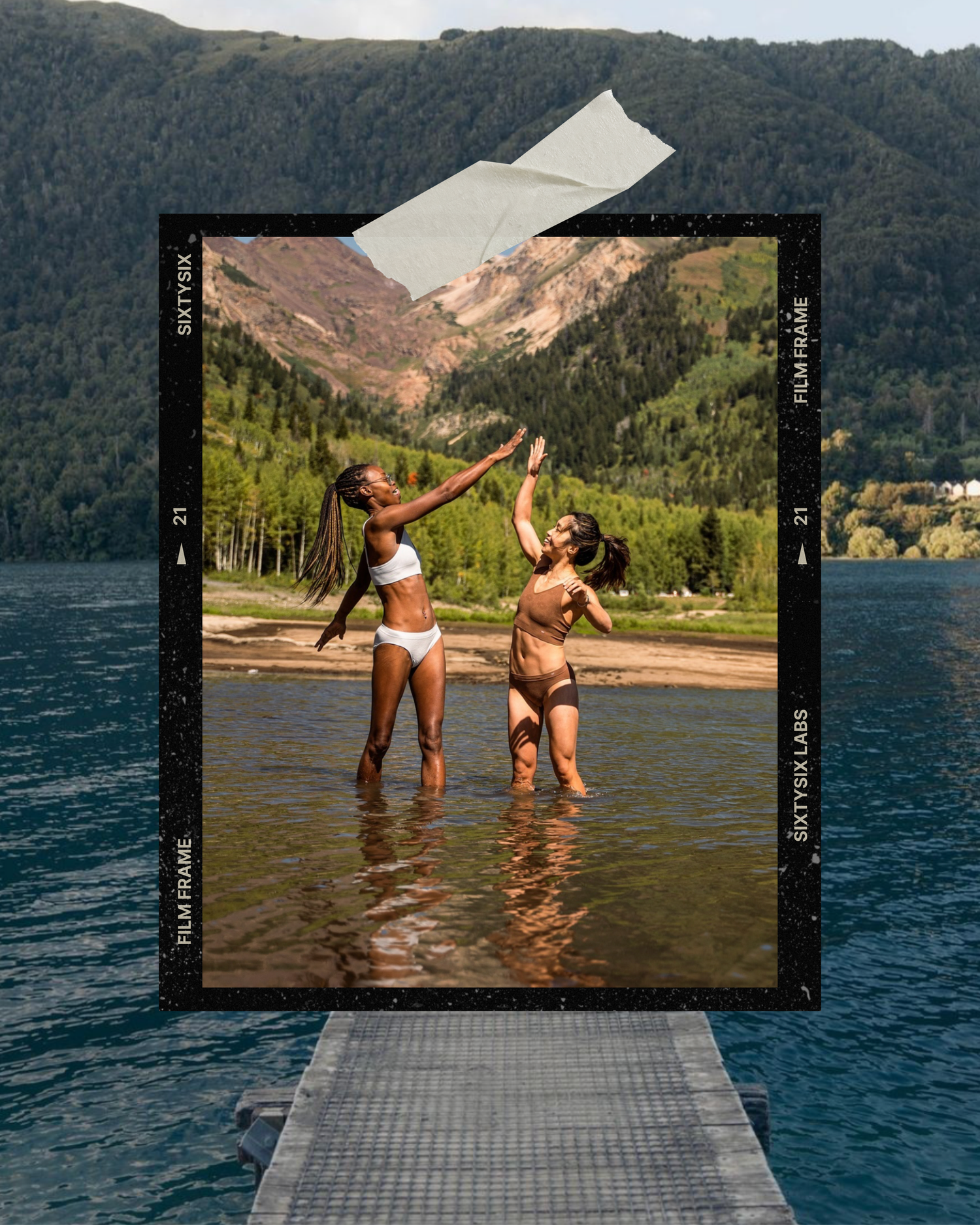Two people in swimwear splash and play in shallow mountain lake waters on a sunny summer day.