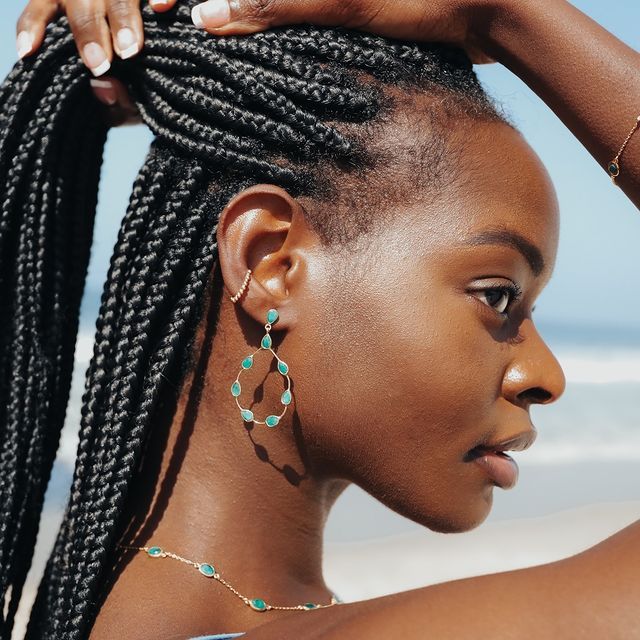 Profile view of an elegant hairstyle with long braids and a statement earring.