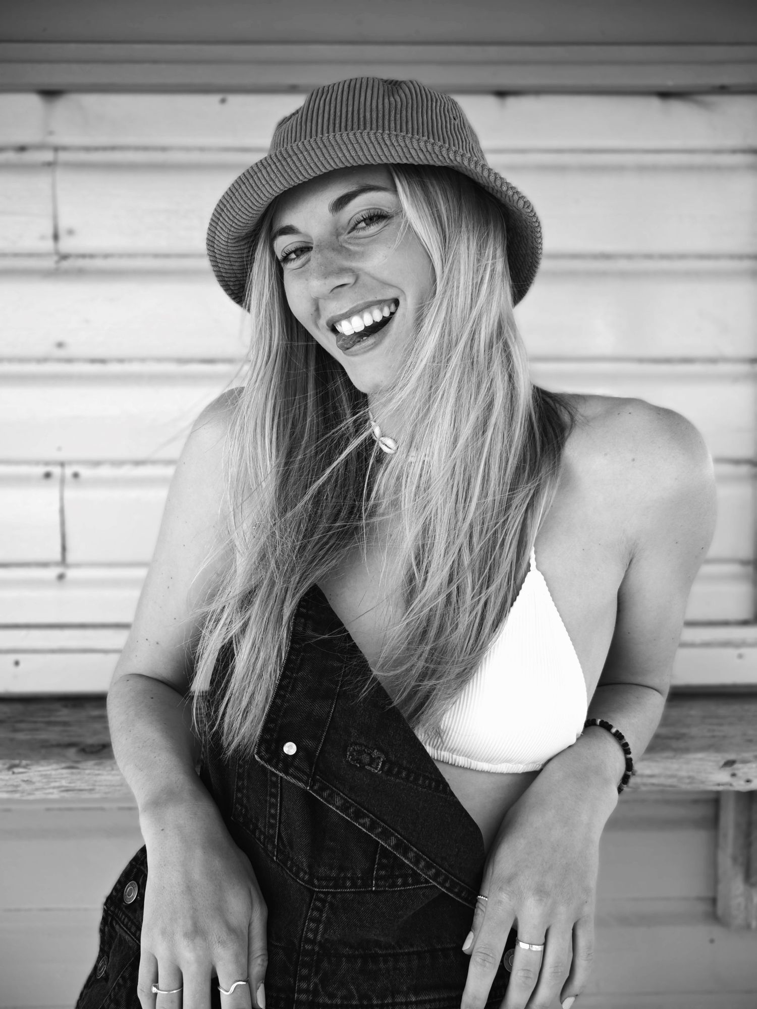 Black and white portrait series showing a person in a hat laughing and posing playfully in casual denim attire.