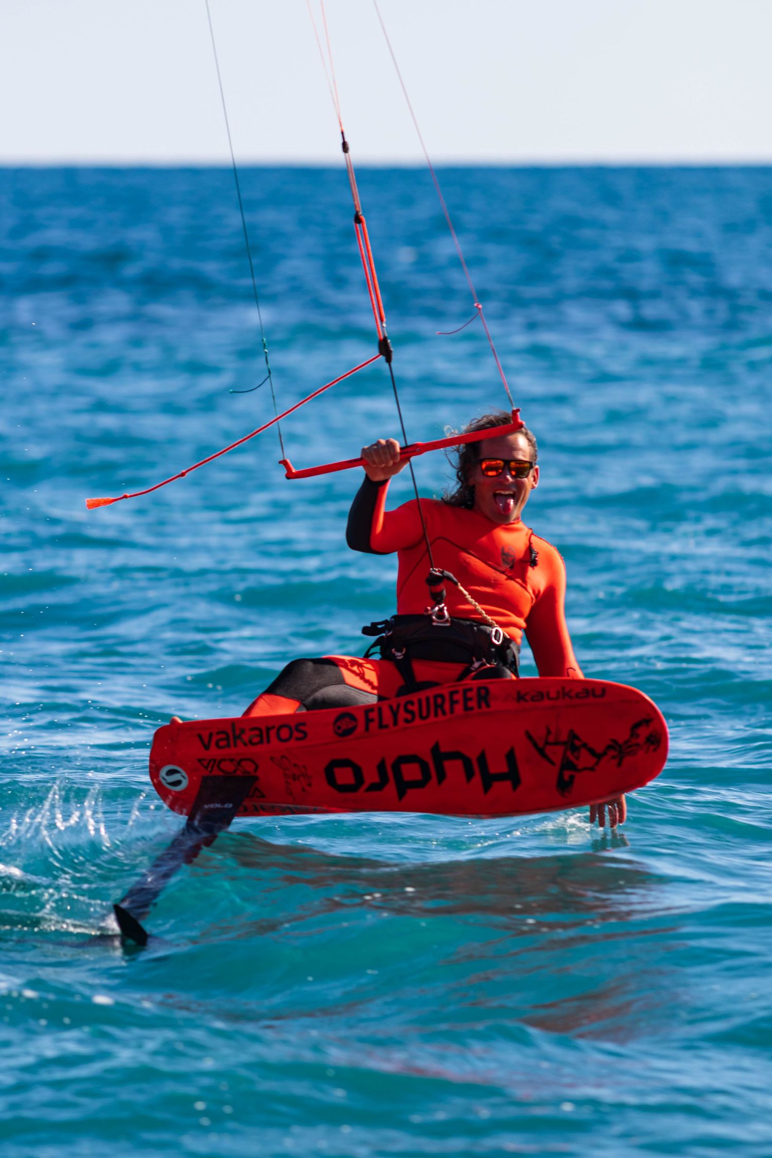 Kitesurfer in red riding on blue water with vibrant wakeboard. UGC campaign.