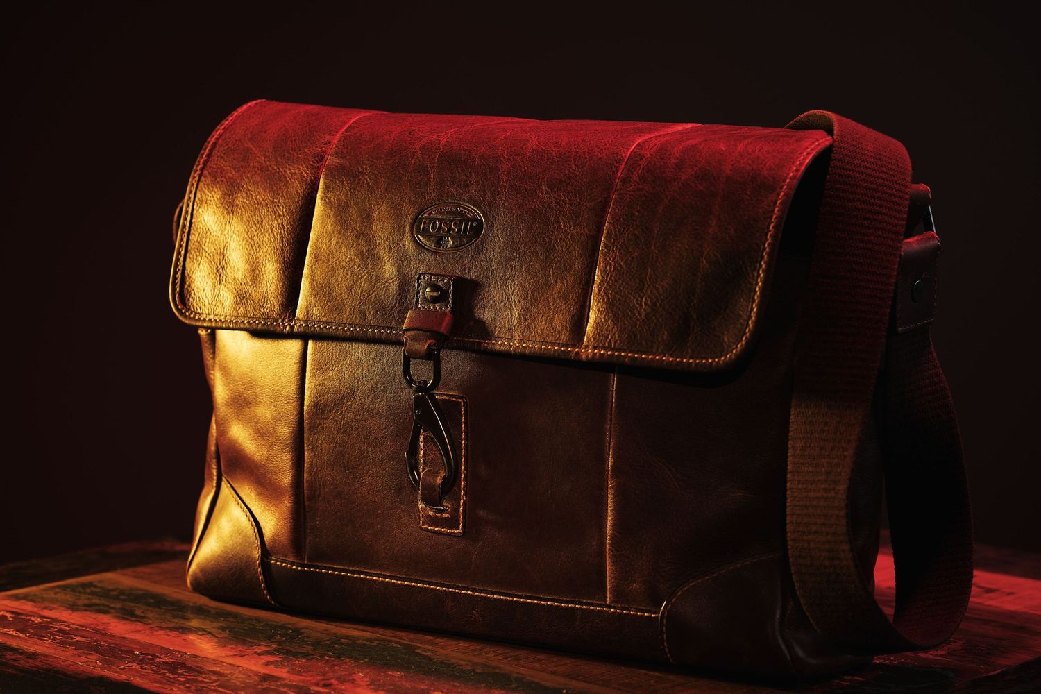 Vintage brown leather messenger bag photographed in dramatic lighting.