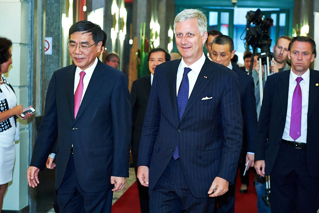 Group of officials walking through a formal corridor.