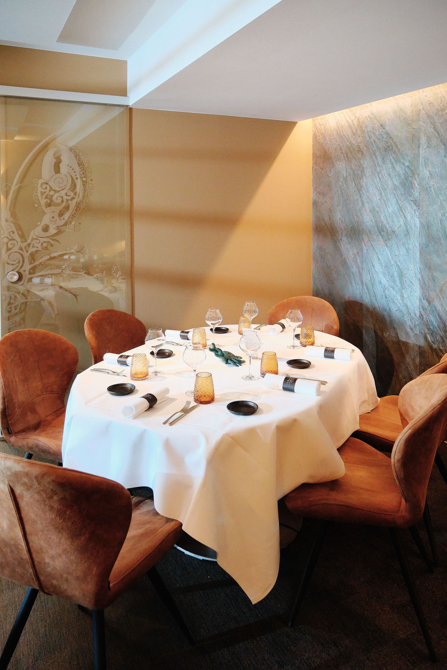 Upscale restaurant dining area with white tablecloths and plush brown velvet chairs.