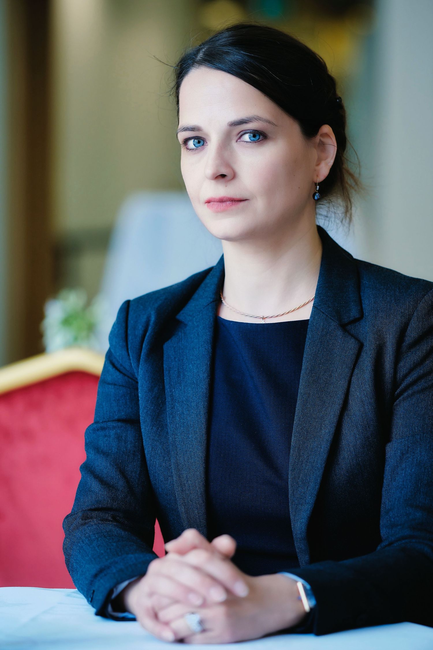 Professional wearing a navy blazer sits at a conference table in an office setting.