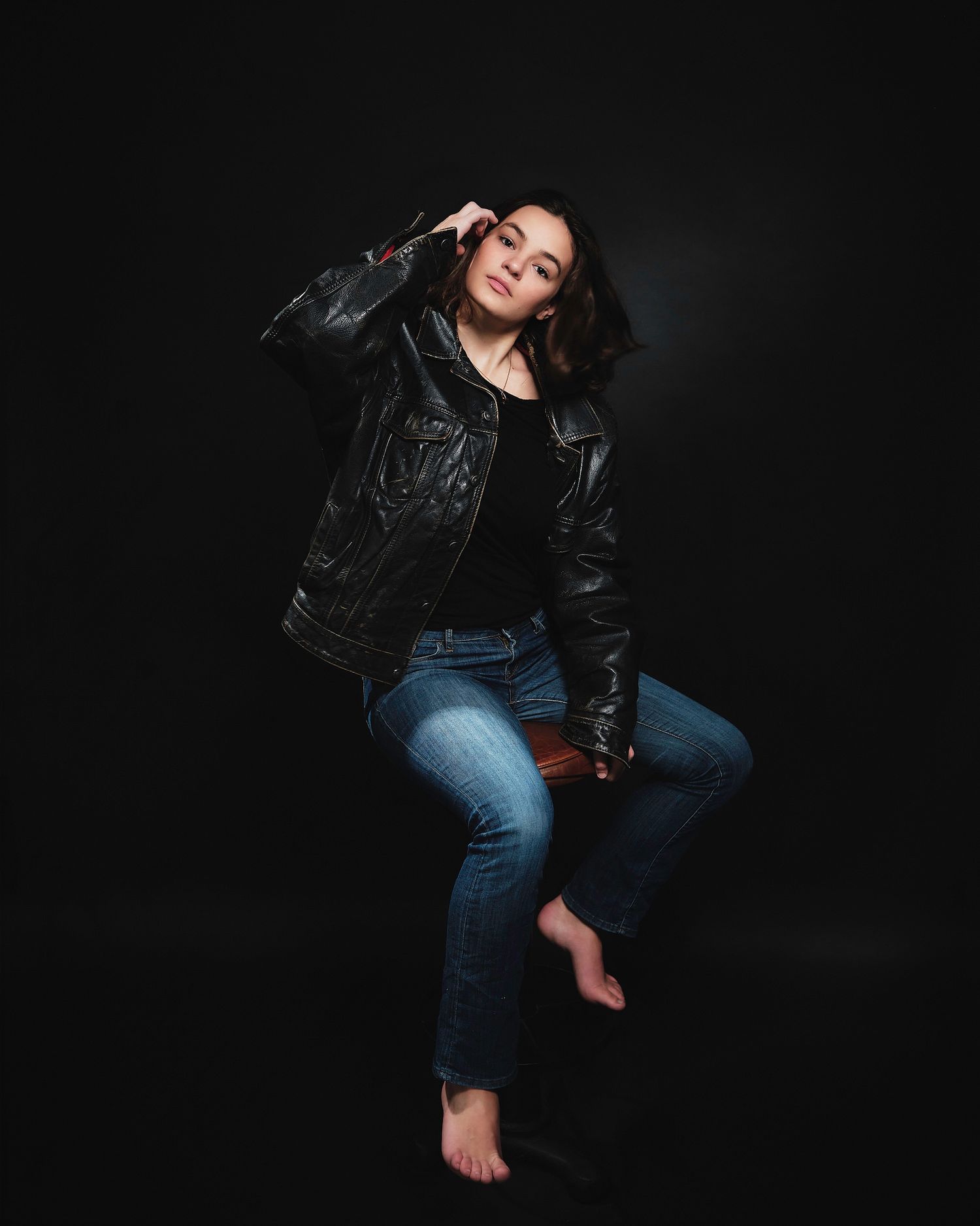 Casual portrait session against black background wearing leather jacket and jeans.