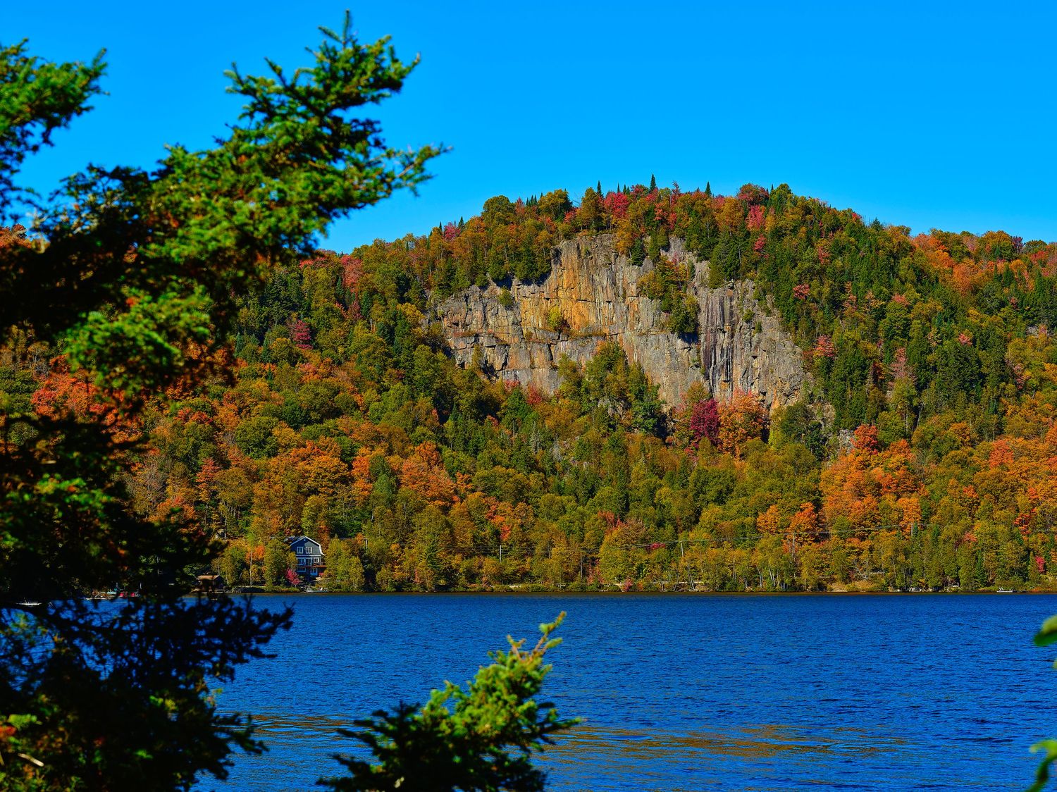 Panoramic autumn landscape of colorful fall foliage around a serene lake in the mountains.