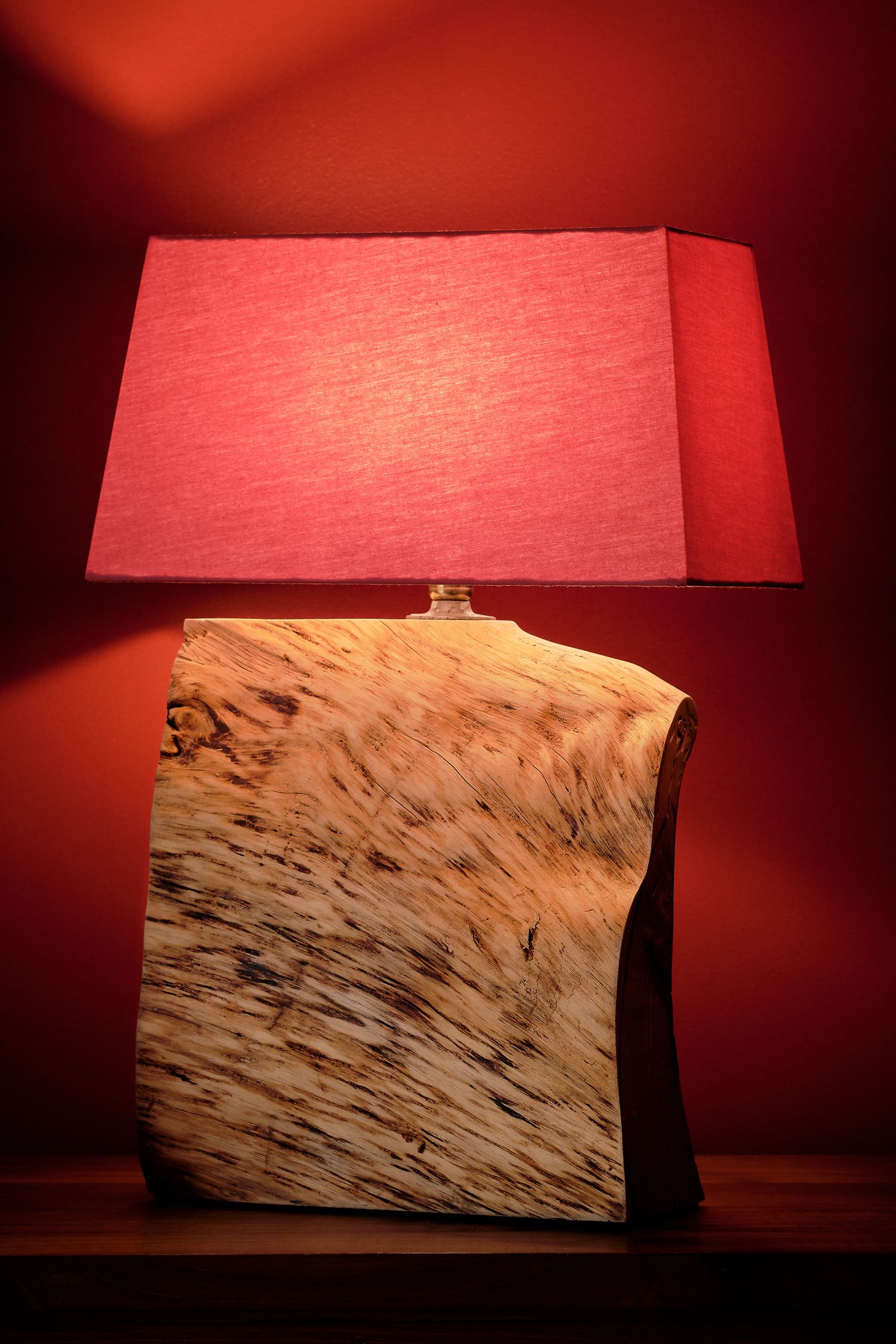 A series of artistic lamp shades casting a warm red glow against a dark background.