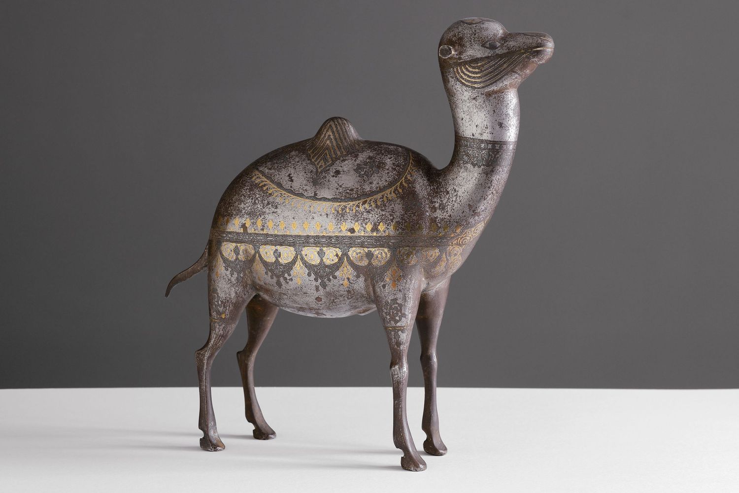 Vintage decorative metal camel sculptures displayed against a gray background.