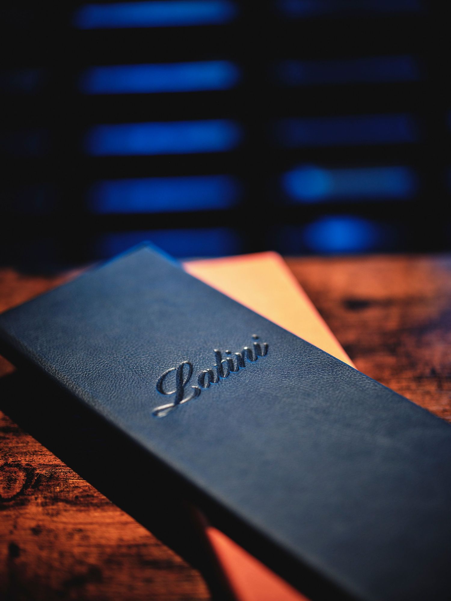 Close-up of an embossed black leather menu cover on a wooden surface.