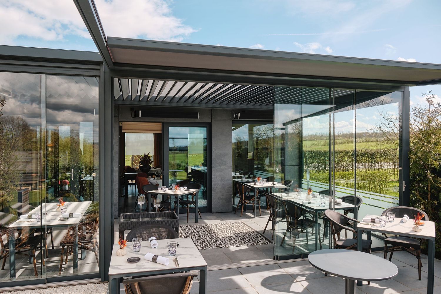Modern glass-walled restaurant terrace offering panoramic views of the surrounding scenery.