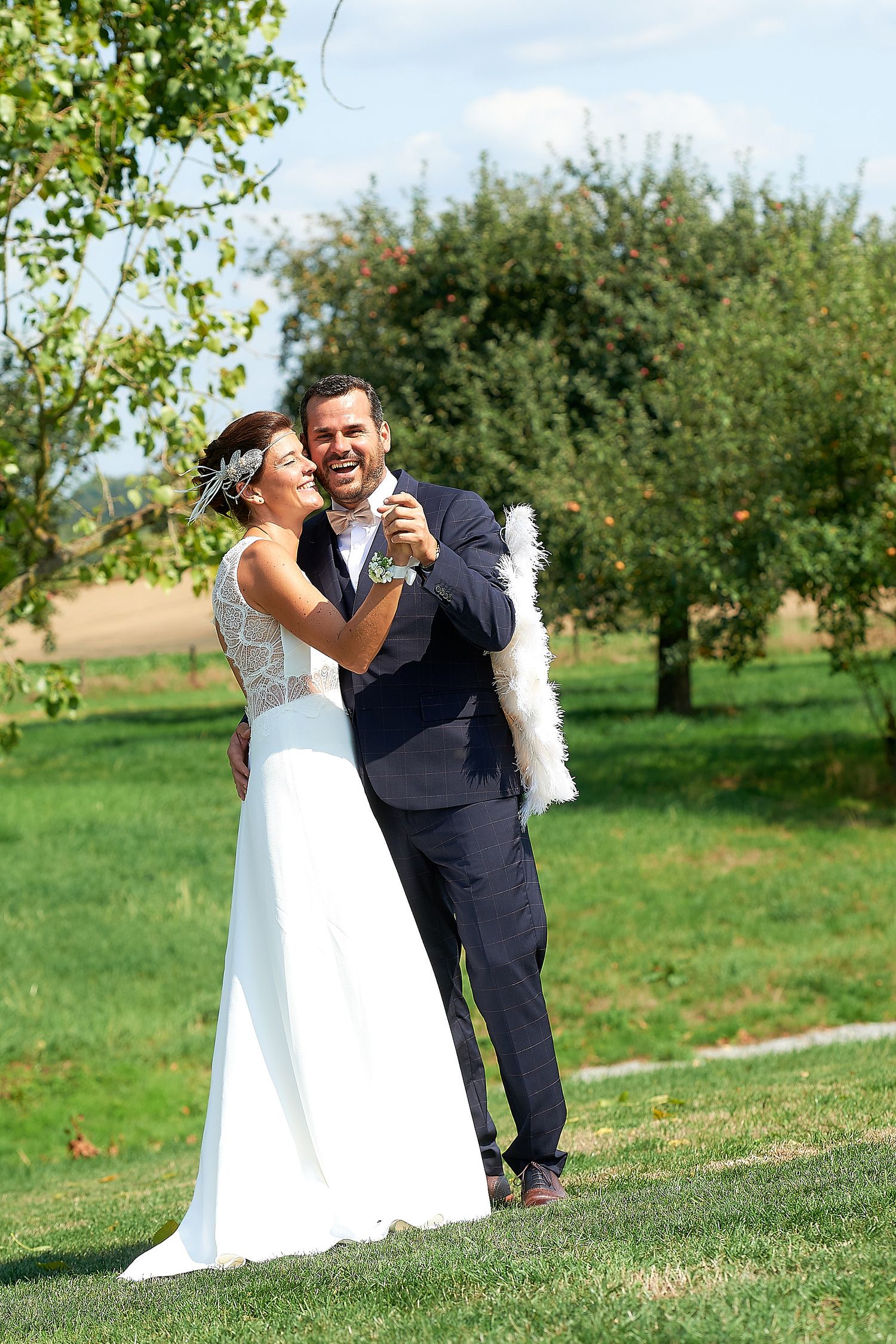 Happy bride and groom laughing together outdoors on their wedding day in a lush green garden setting.