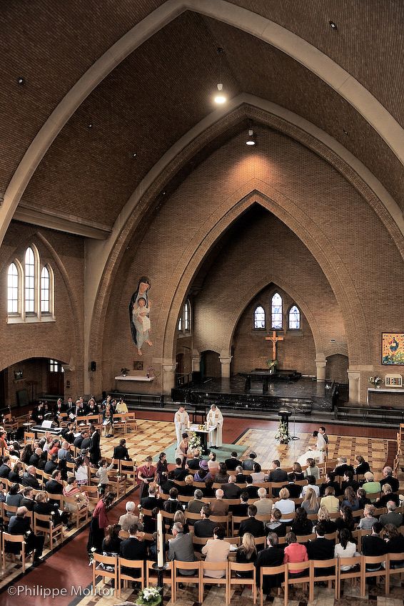 Interior view of Gothic brick church filled with congregation during religious ceremony.