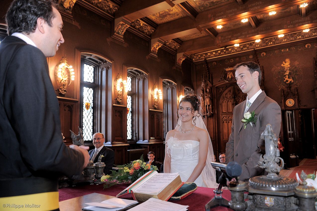 Couple exchanging wedding vows at an ornate wooden altar in an elegant historic ceremony hall.