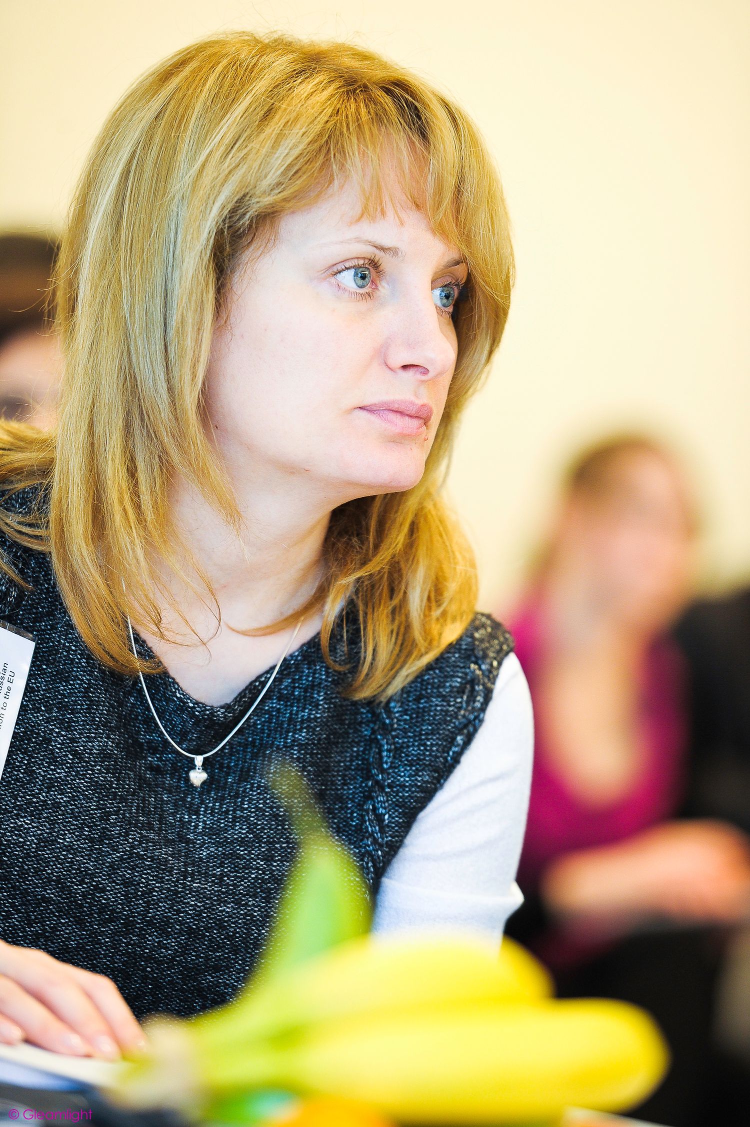 Professional conference attendee in dark sweater participating in discussion.