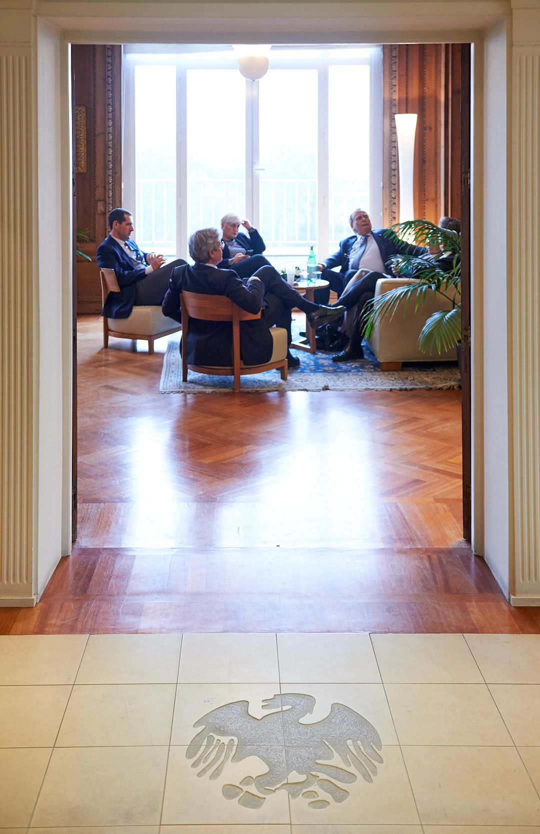 Elegant office lounge with hardwood floors and classical columns featuring eagle motif inlay.