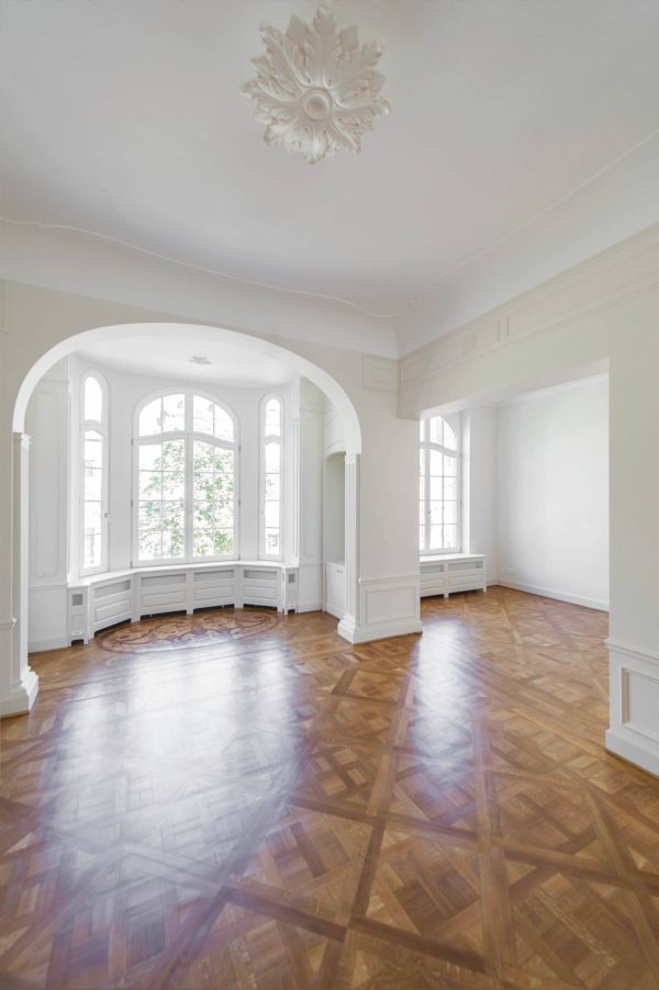 Elegant room with arched bay windows, ornate ceiling medallion, and parquet flooring.