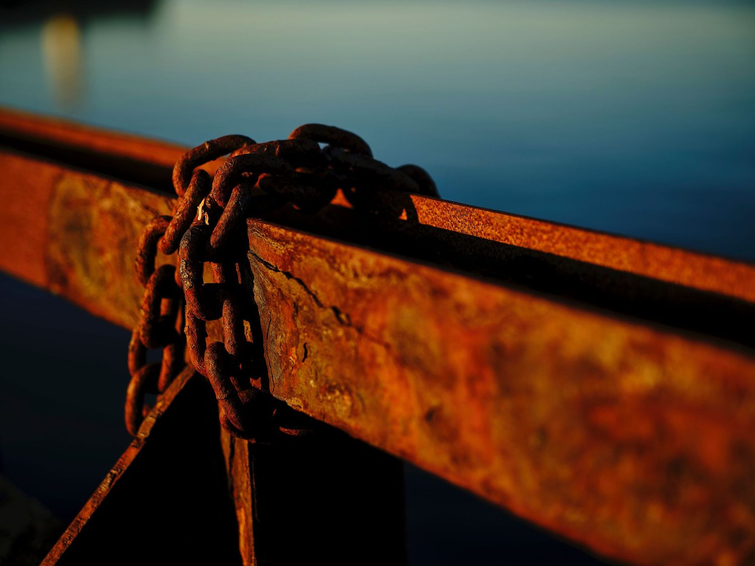 Close-up of weathered rusty metal beams silhouetted against a deep blue sky.