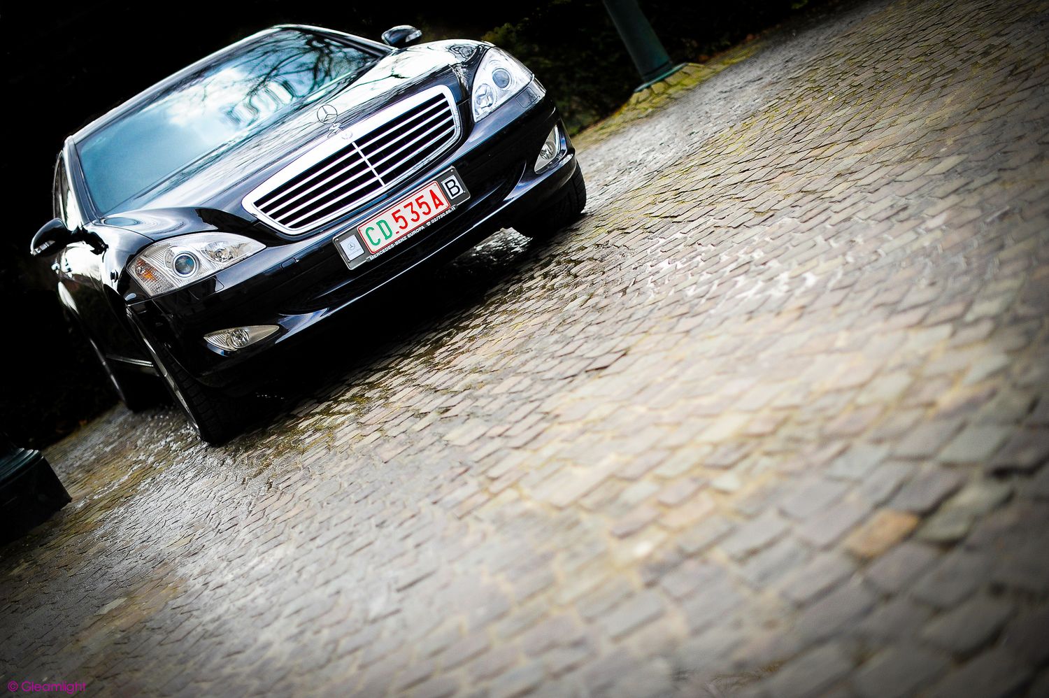 Row of luxury Mercedes-Benz vehicles parked on cobblestone street.