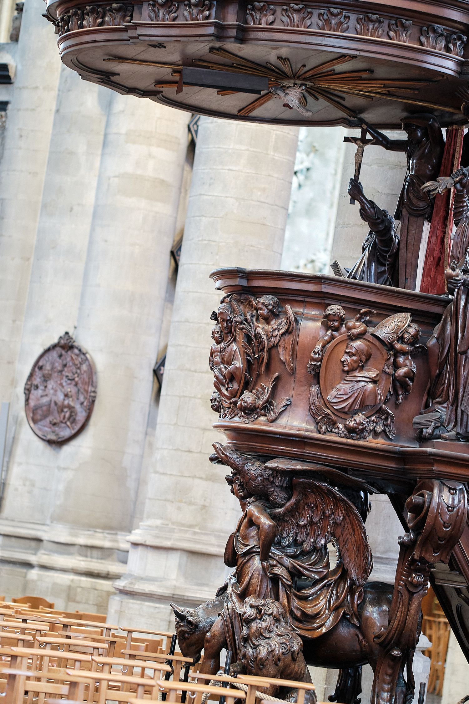 Ornate carved wooden pulpit with angels and figures in a Gothic cathedral interior.