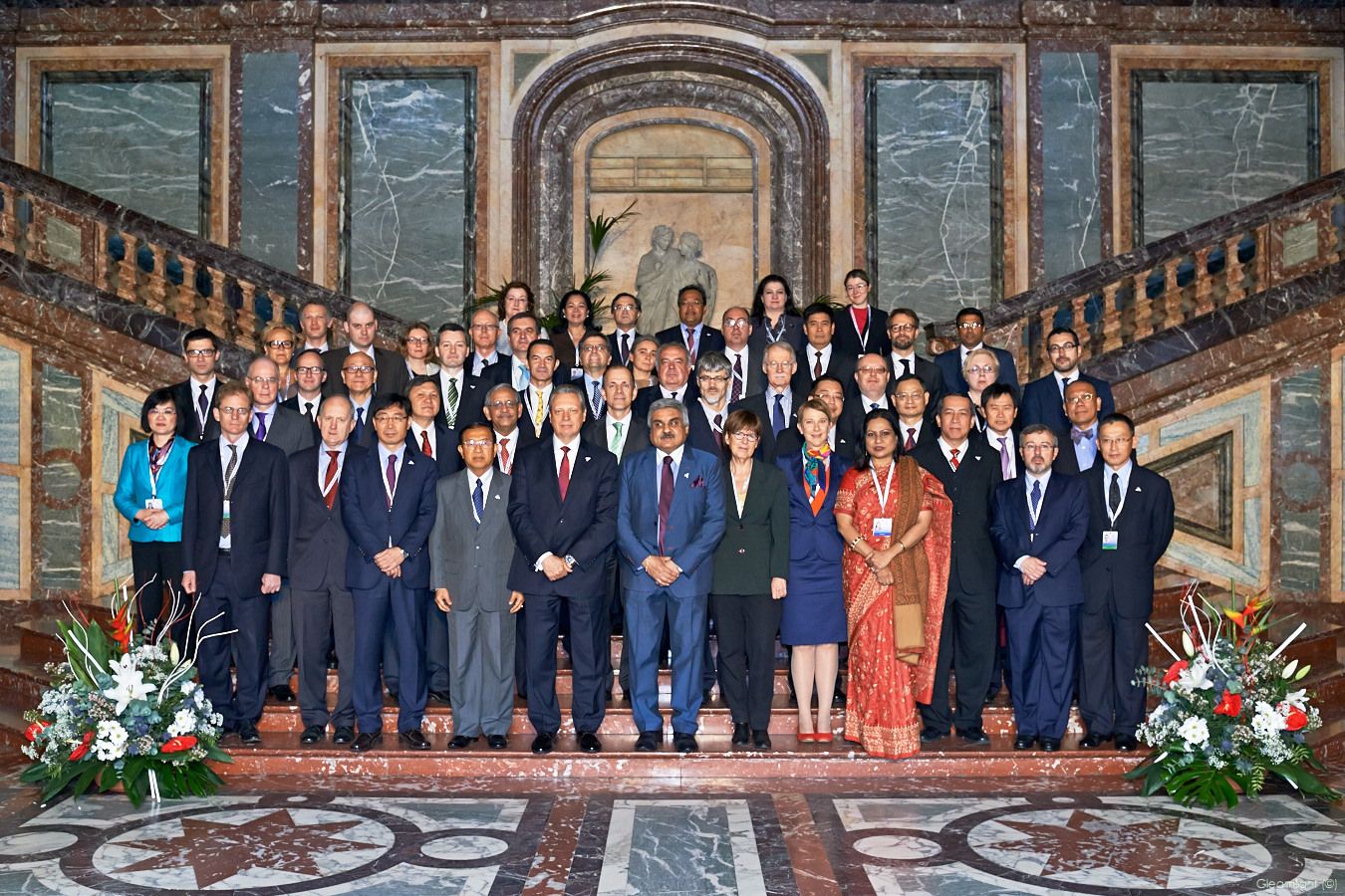 Large group photo of formally dressed people in an ornate historic building interior.