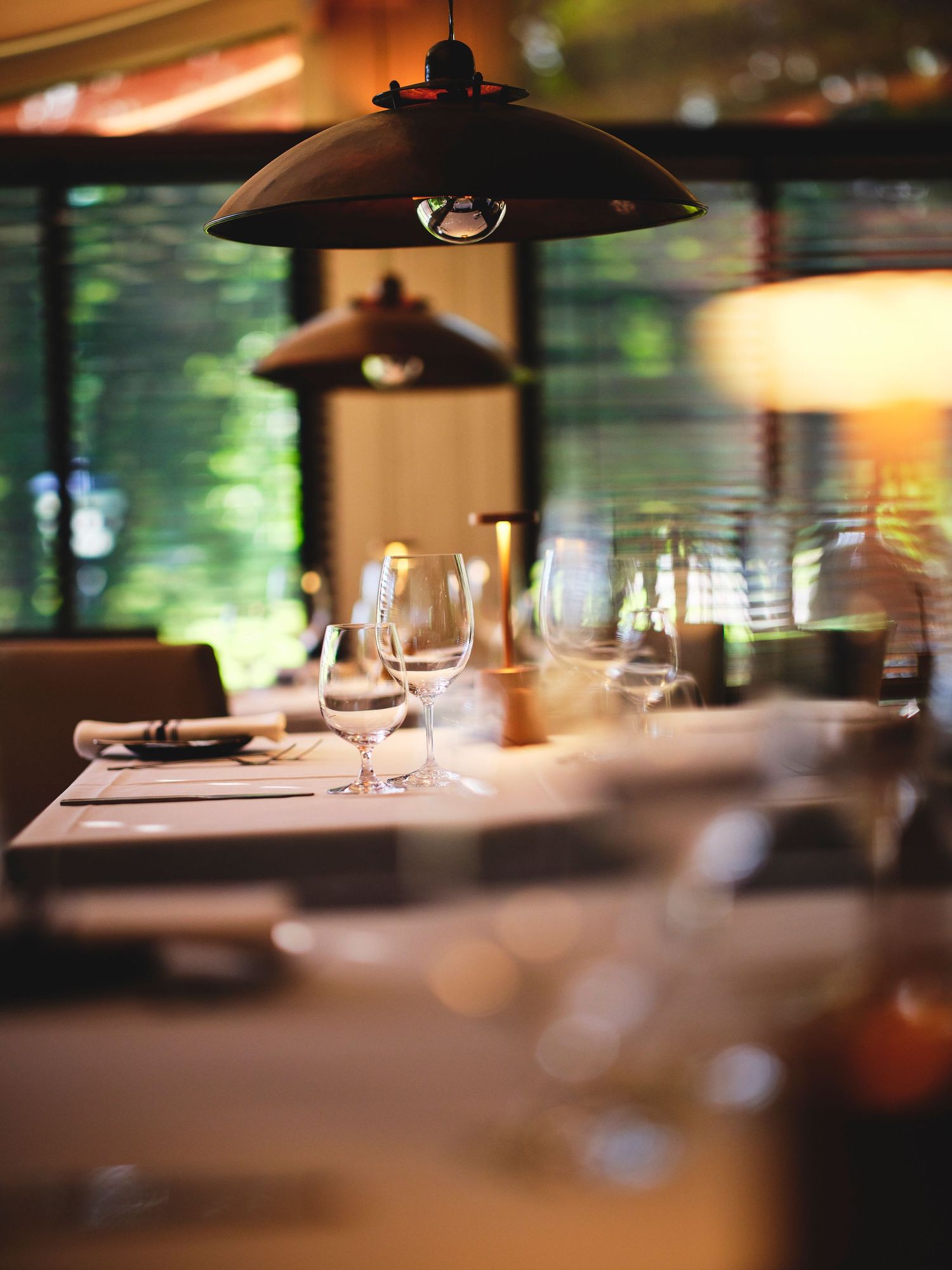 Elegant restaurant table settings with pendant lighting and blurred background creating intimate ambiance.