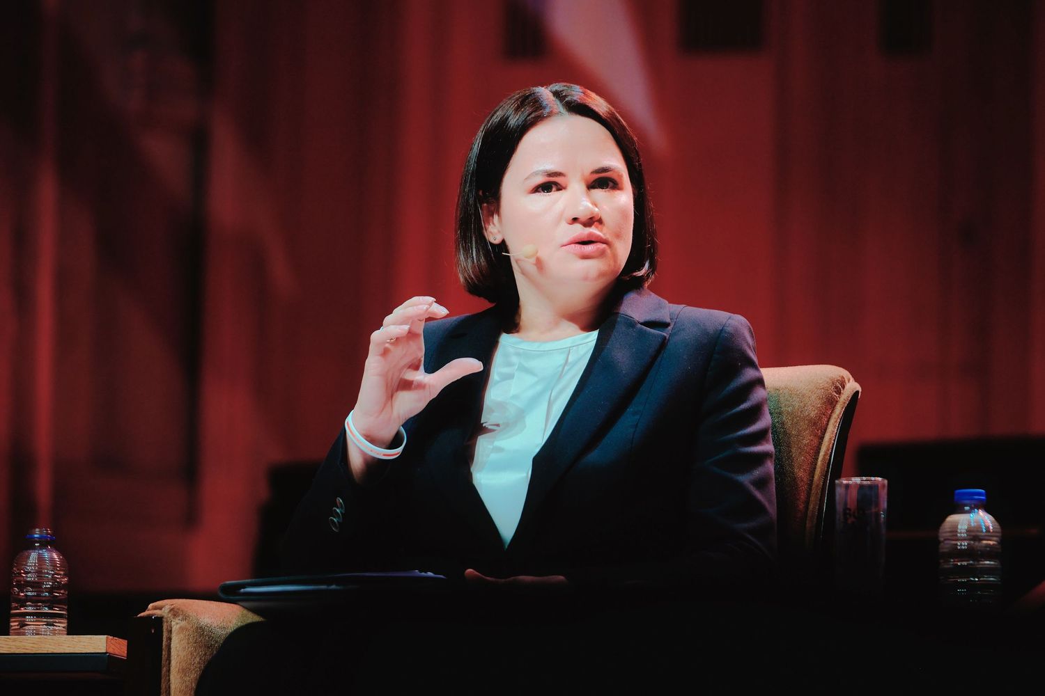 Professional discussion panel on stage with red backdrop lighting.