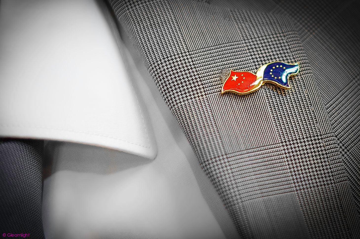 Close-up detail of national flag pins on formal business attire.