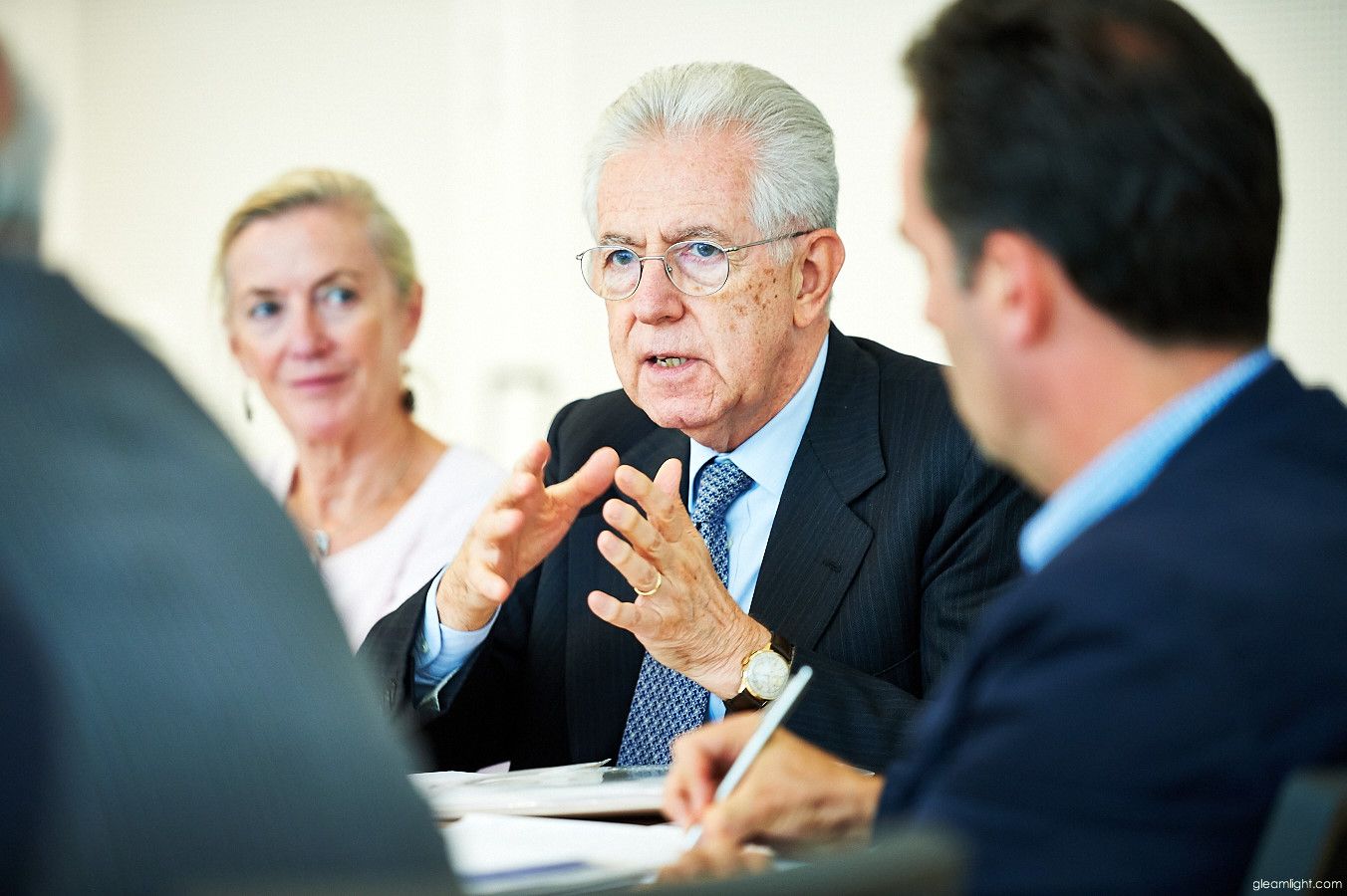 Business people engaged in discussion at a conference table with natural lighting.