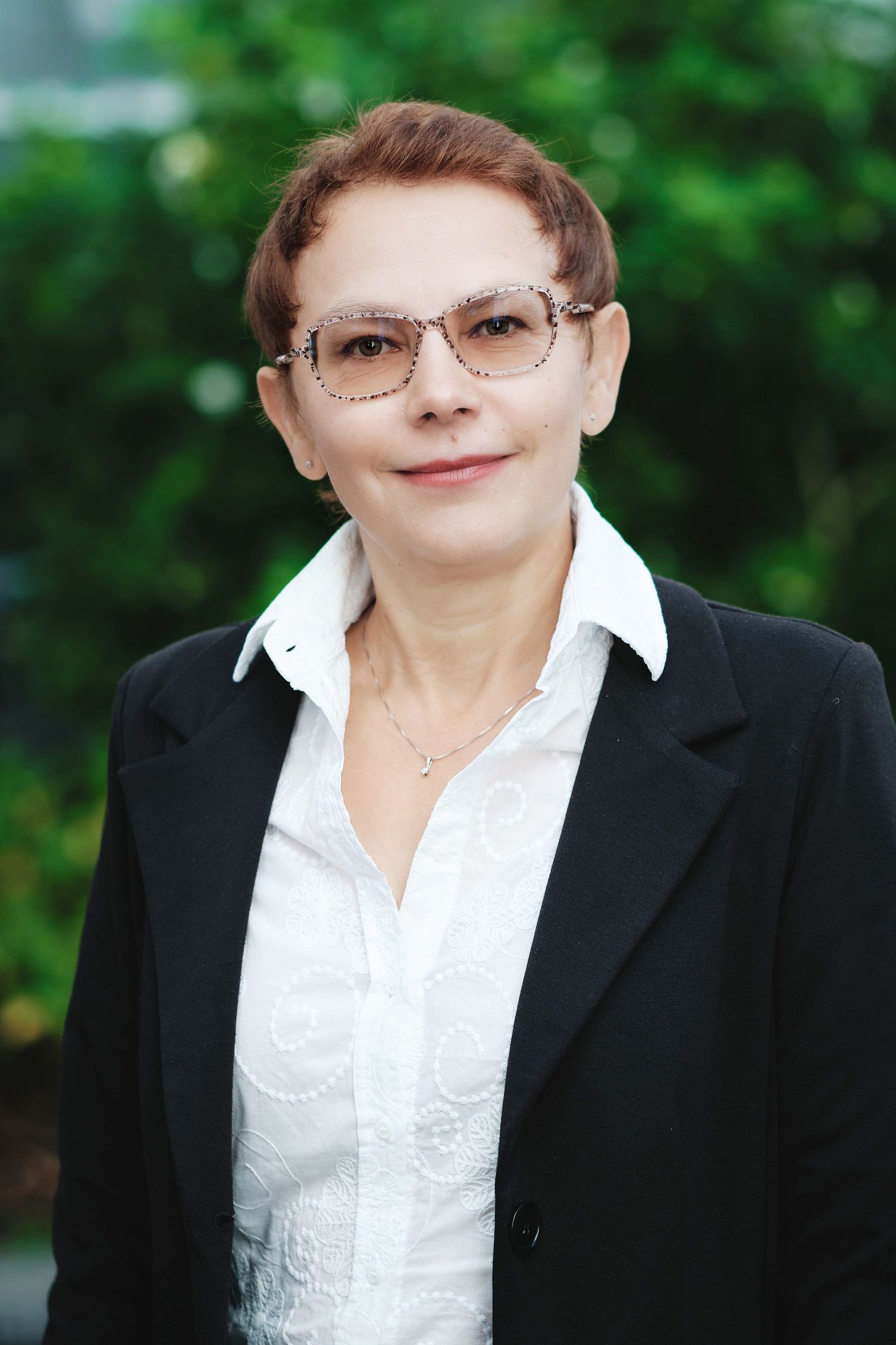 Professional headshots wearing black blazer and white blouse with glasses outdoors.