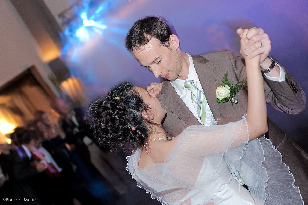 Bride and groom share their first dance at a wedding reception under blue ambient lighting.