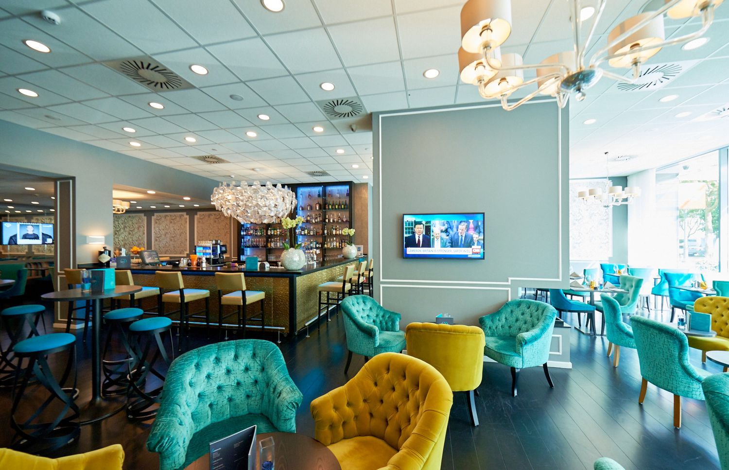 Stylish lounge area with turquoise and yellow tufted chairs and modern lighting.