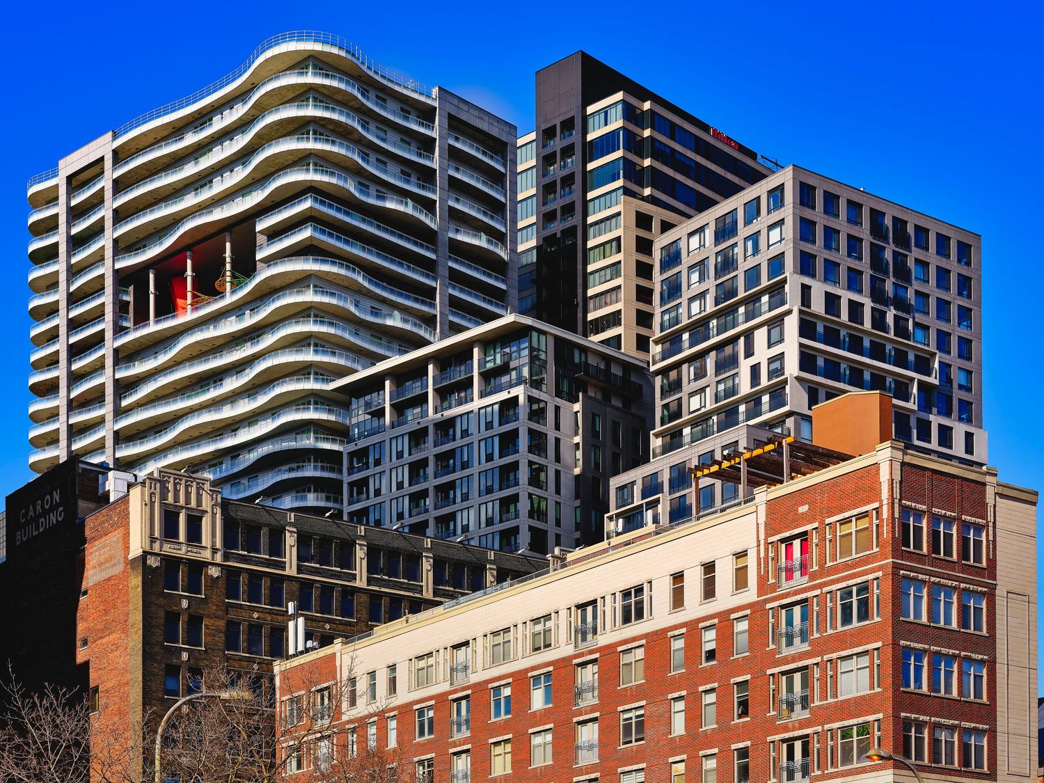 Modern high-rise apartment buildings with brick facades against a bright blue sky.