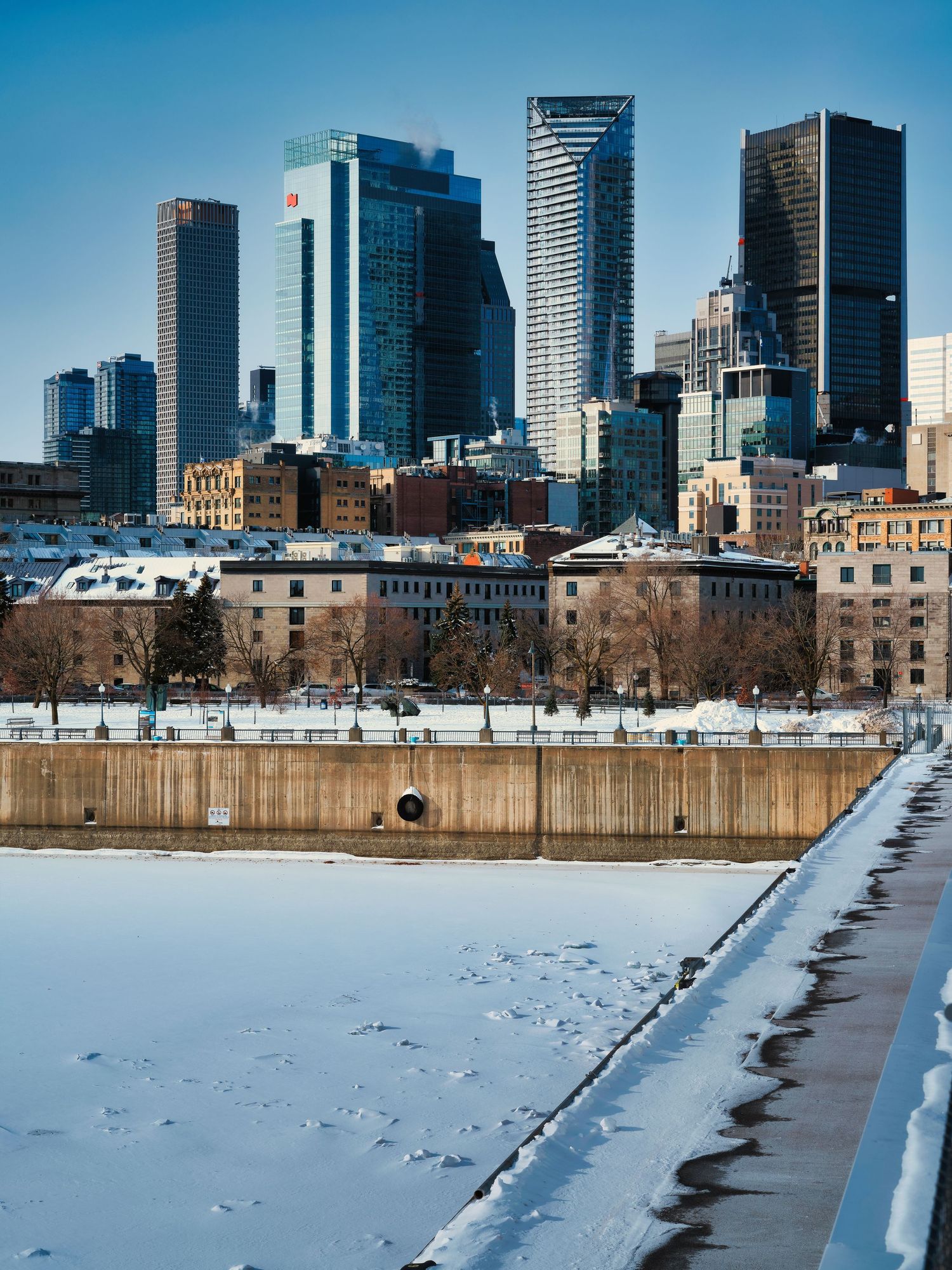 Winter cityscape of Minneapolis skyline reflecting in frozen Mississippi River with snow covered riverbank.