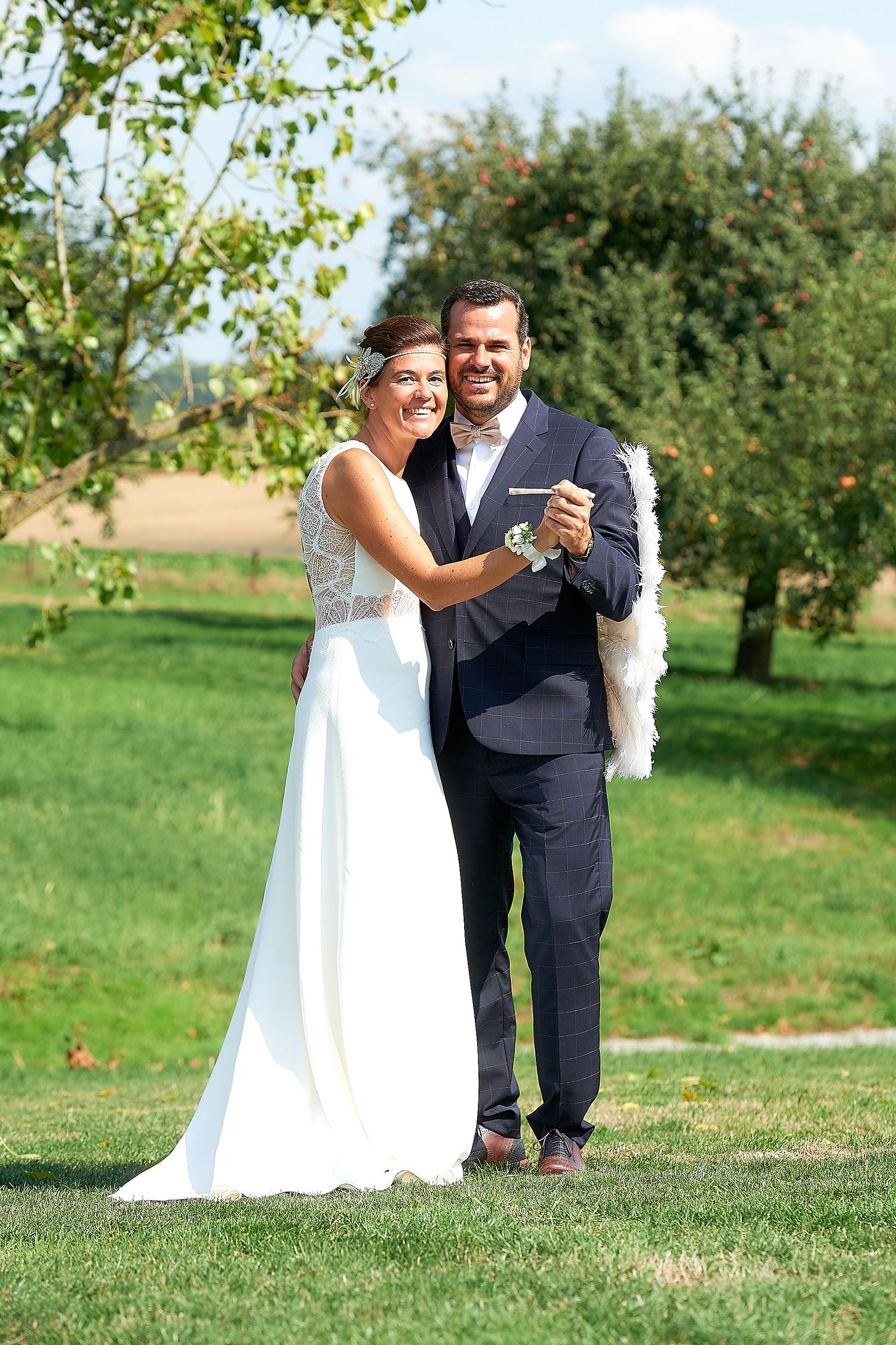 Happy bride and groom posing outdoors in a lush green garden on their wedding day.