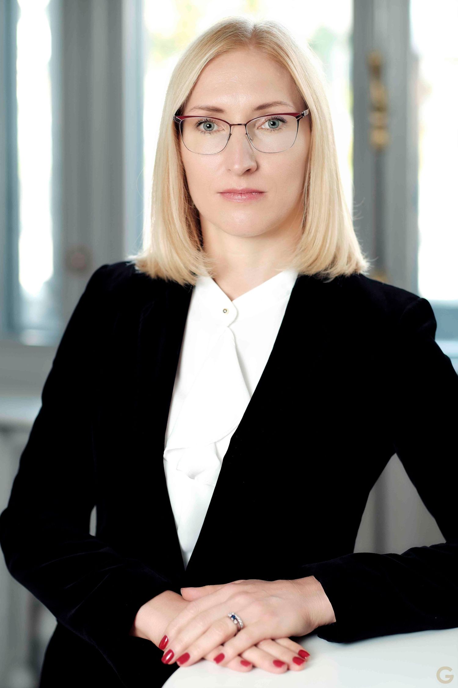 Professional portraits of person in black blazer and white shirt against bright background.