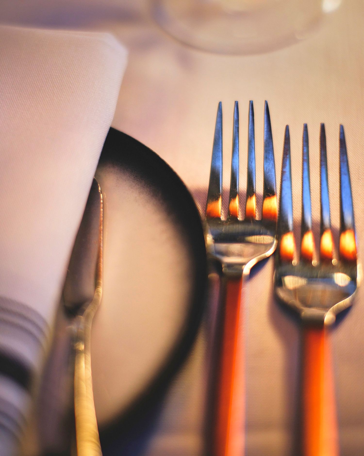 Close-up sequence of silver forks arranged in a row with soft focus and warm lighting effects.