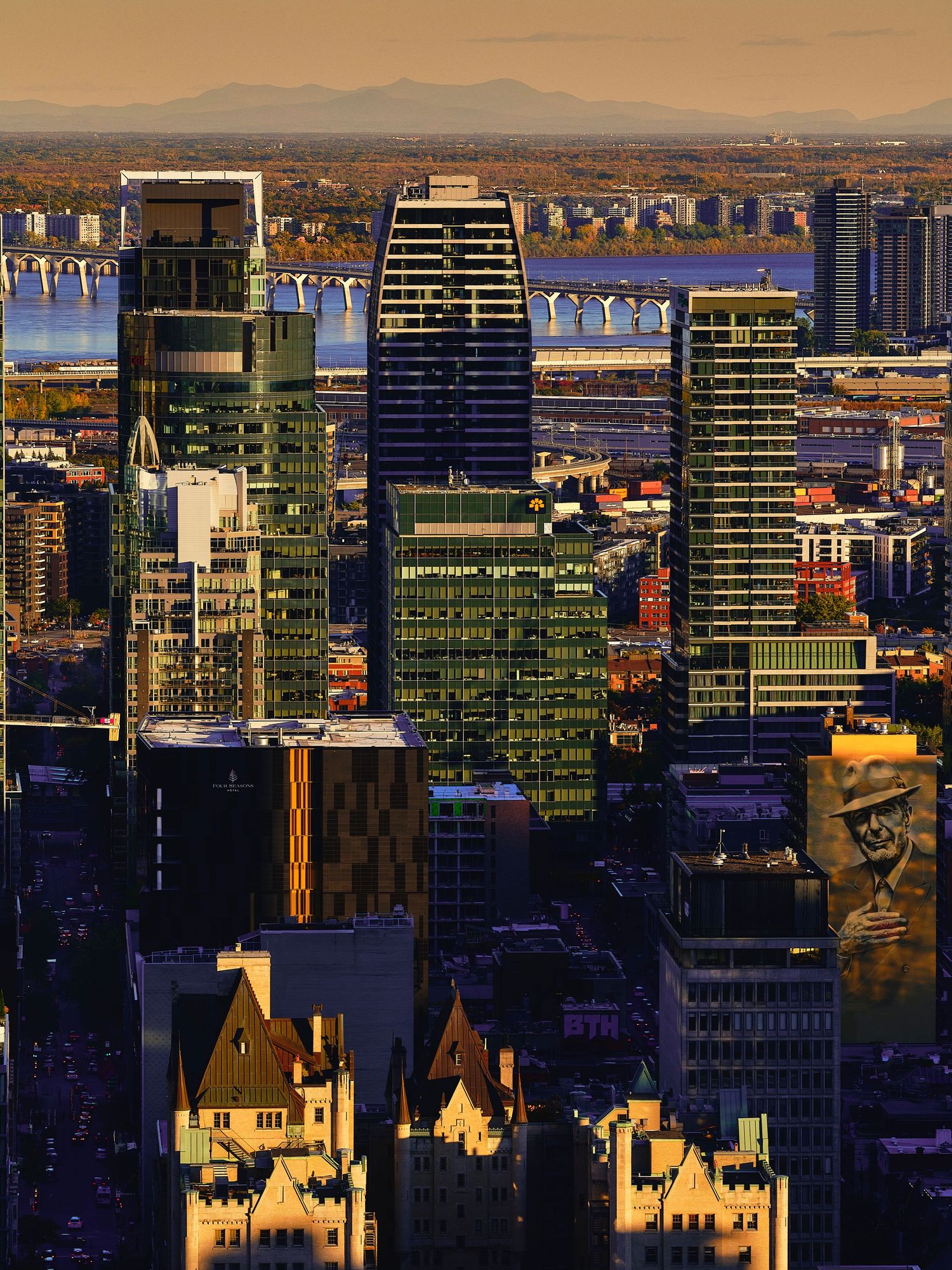 Modern glass skyscrapers and historic buildings create a dramatic urban skyline at sunset with golden light.