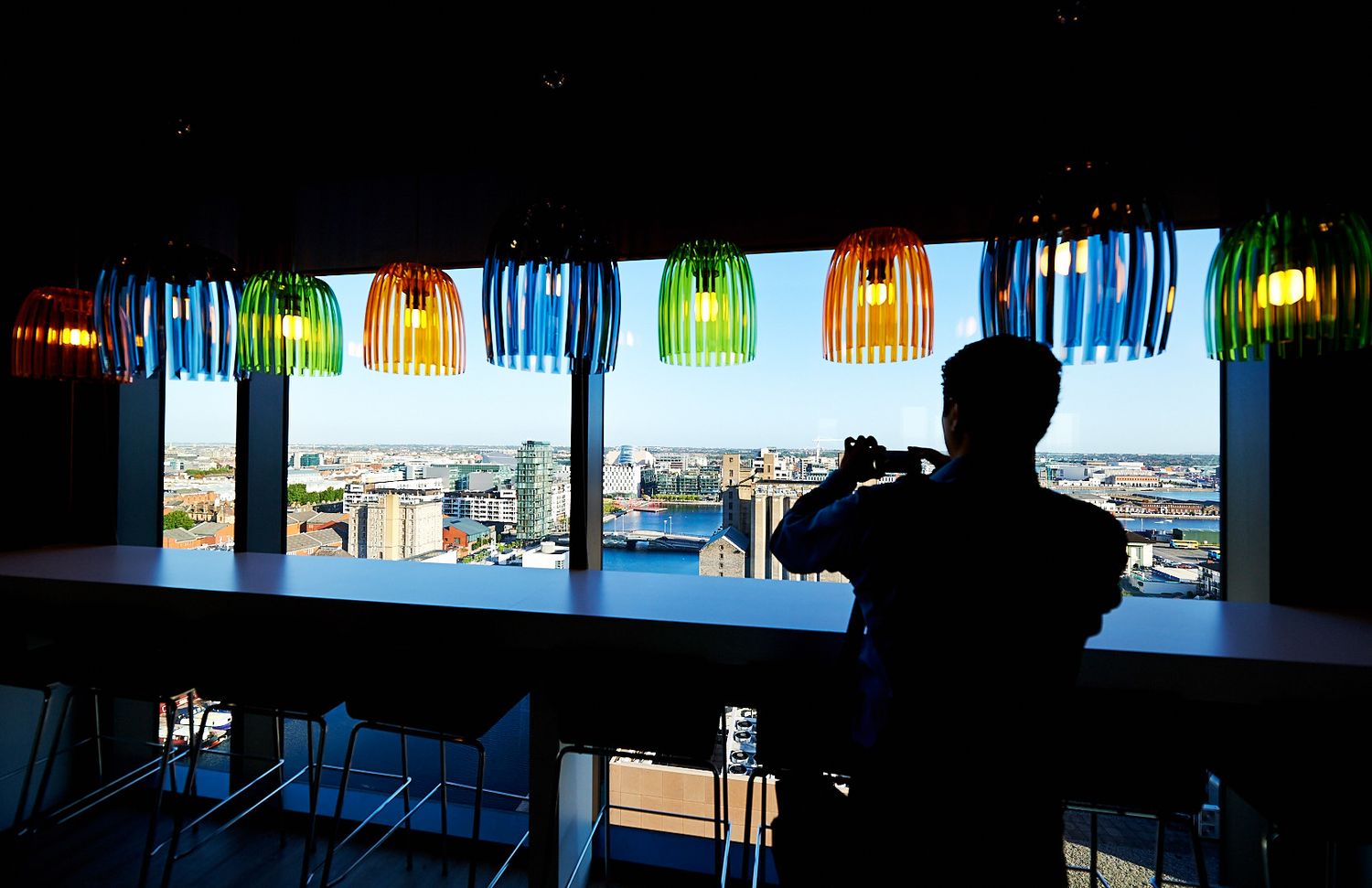 Silhouetted figures in office space with colorful window treatments.