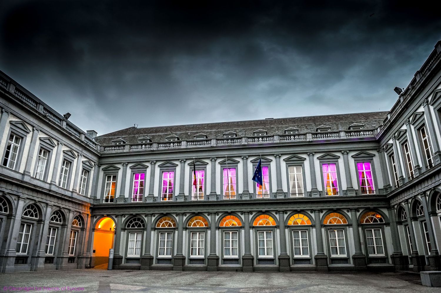Panoramic view of a neoclassical building exterior with illuminated arches and colorful lighting displays.
