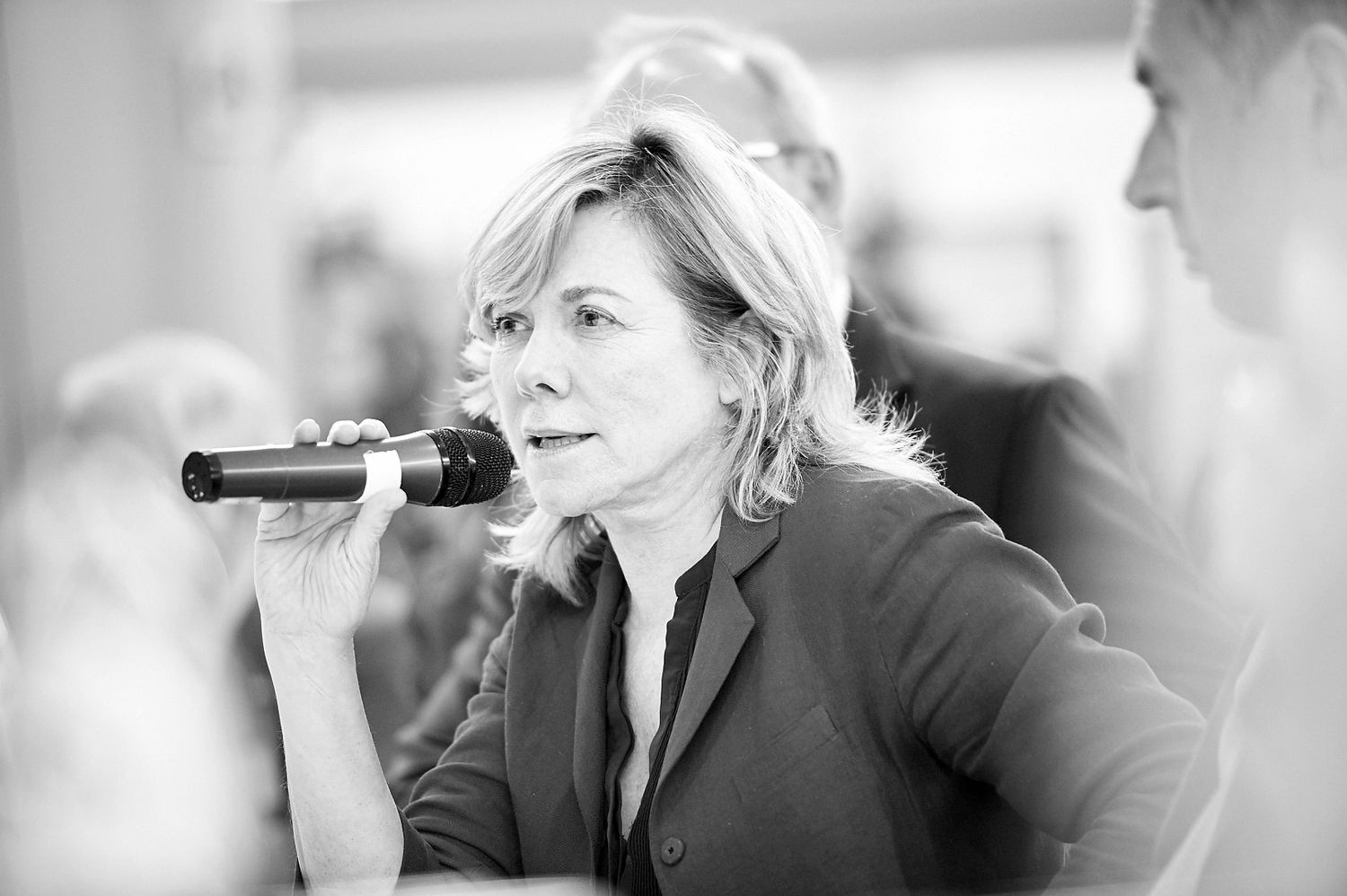 People speaking into microphones during a corporate event or conference.