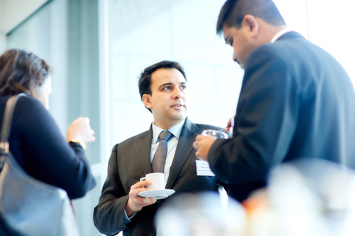 Business professionals having coffee and networking during a conference break.