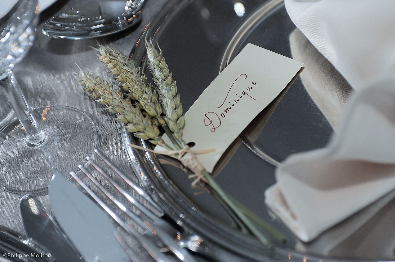 Elegant wedding table setting with wheat stalks and a name card reading Dominique on a silver plate.