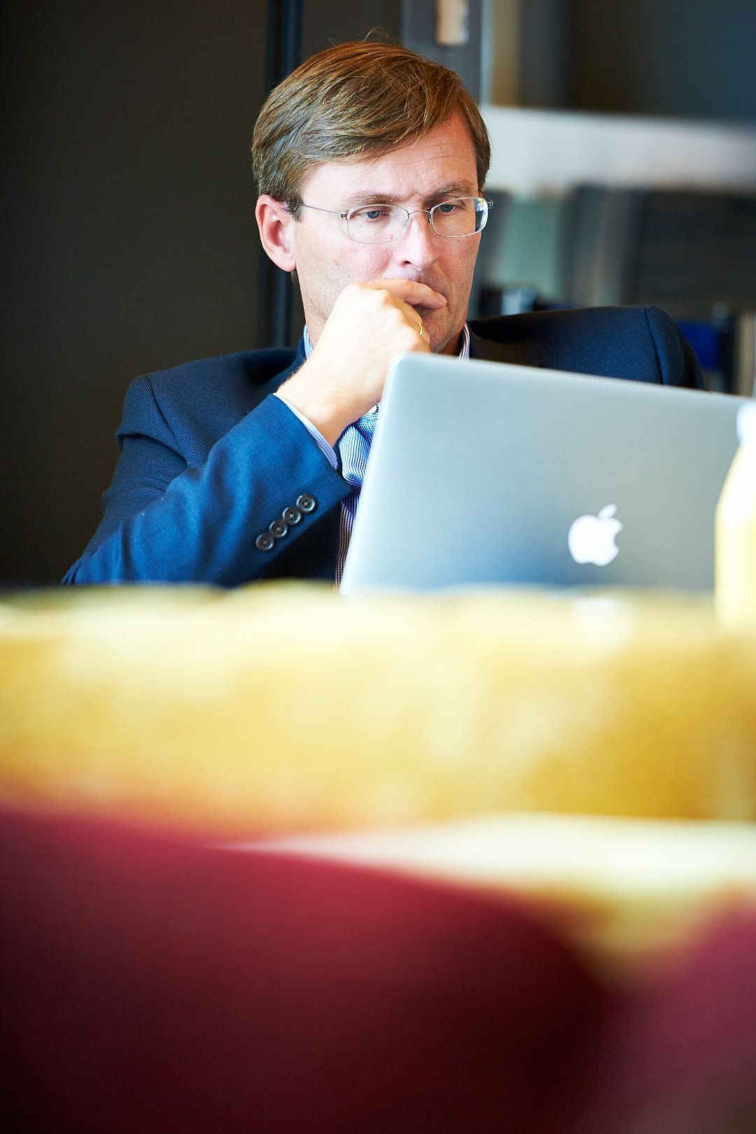 Professional working on Apple laptop in office meeting space.