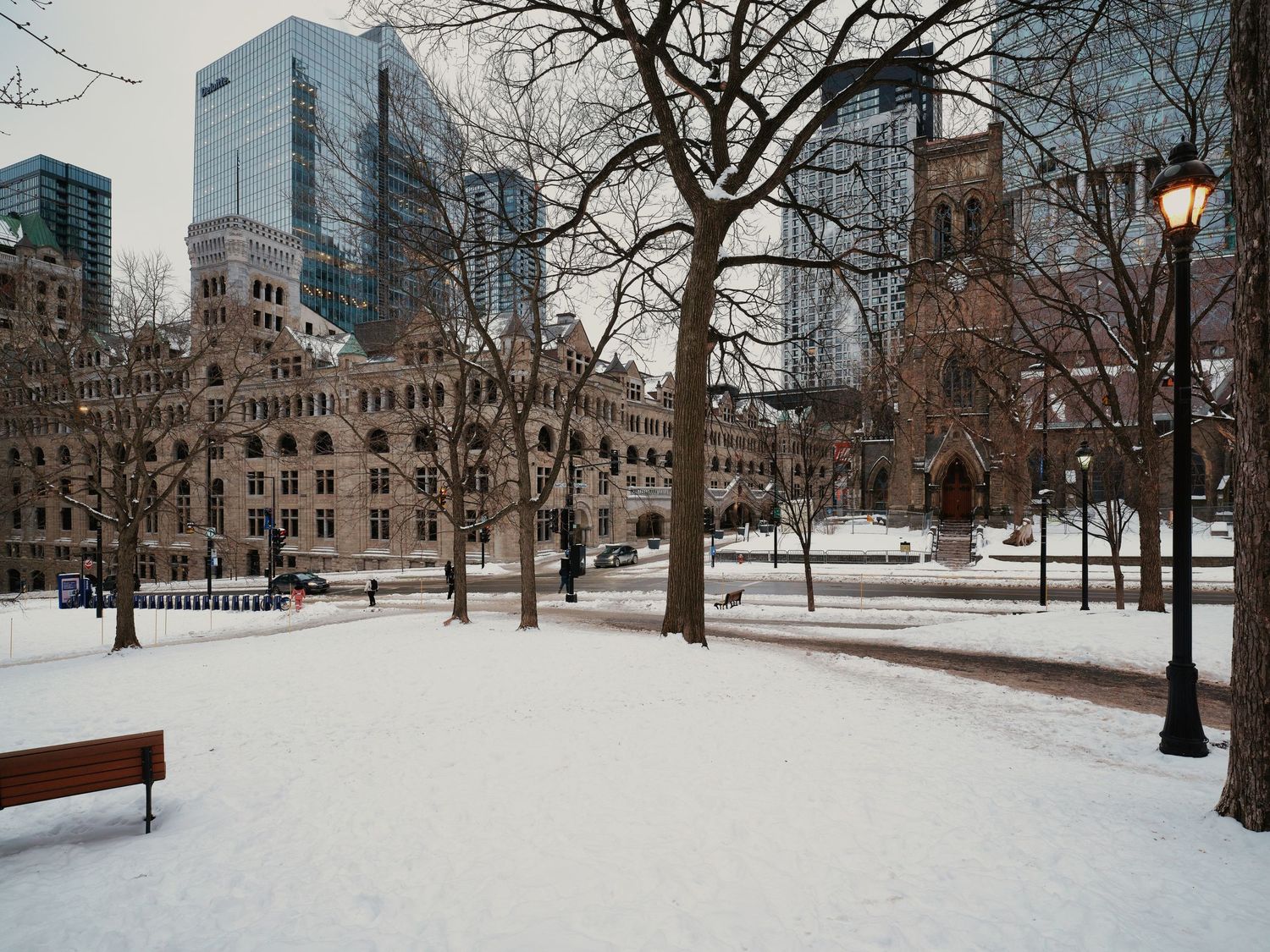 Snow-covered university campus quad with historic buildings and bare winter trees.