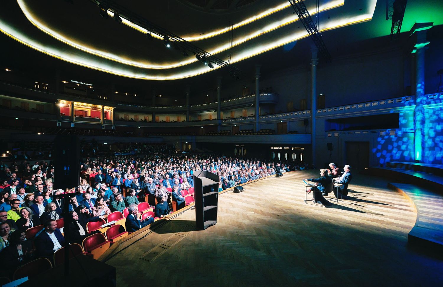 Wide-angle view of a conference hall with dramatic lighting and audience seating.