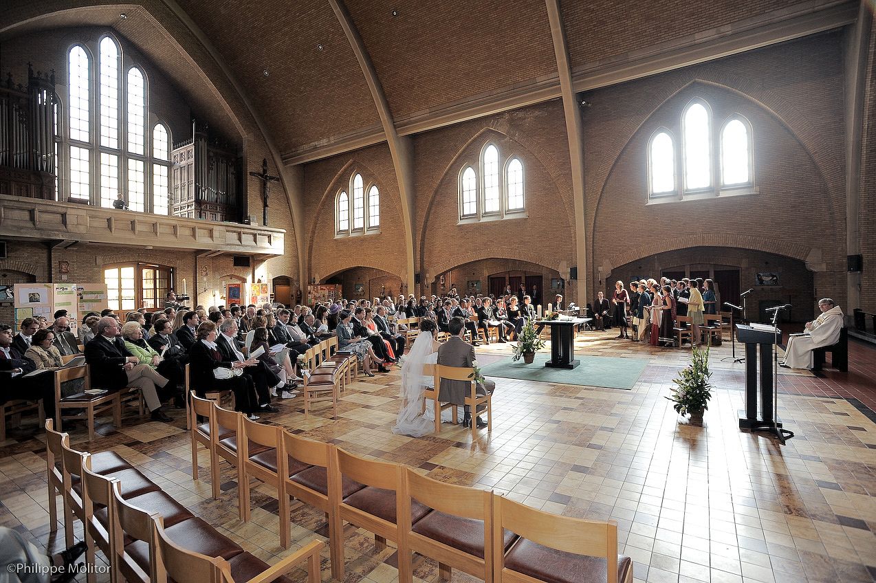 Large congregation gathered in a Gothic brick church hall with arched ceilings during a formal ceremony or service.